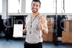 Ive worked out a schedule for you. a young man showing thumbs up while using a digital tablet in the gym.