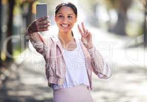 Wishing you all a healthy and safe day. a sporty young woman making a peace sign and taking selfies while exercising outdoors.