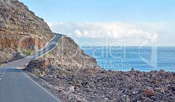 La Palma island mountain highway for a drive to the cliff top on a winding road by the ocean. Sight seeing by the coast in Spain Curved seaside route with cloudy blue sky and the sea on a background.