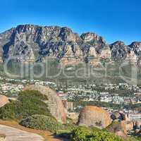 Scenic view of 12 apostles mountain range overlooking nearby homes in the suburb of Camps bay, Cape Town..Landscape of relaxing scenic view with rocks and green bushes on a hiking path in summer