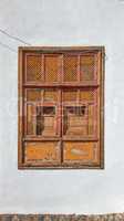 Architecture of an old grey wall with a rusted metal window outside. Exterior texture details of an old rustic residential build with vintage wooden shut windows discovered in Santa Cruz de La Palma