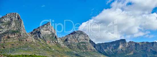 Panorama of majestic mountains against a cloudy blue sky copy space. Beautiful view of The twelve apostles with hills covered in green grass on a popular landmark or sightseeing location in Cape Town