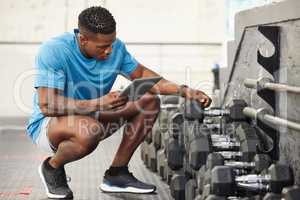 Everything has to be organised in this gym. a muscular young man using a digital tablet while checking equipment in a gym.
