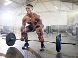 Heavy is not a word I know. a muscular young man exercising with a barbell in a gym.