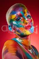 Were meant to see the world in color. Studio shot of a young woman posing with multi-coloured paint on her face.