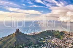 Aerial view of a mountain and ocean near a coastal city on a cloudy day. High angle of Lions Head in a stunning urban scene near a calm sea. Cape Town from above with a blue horizon and copy space