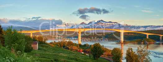 Landscape view of Saltstraumen in Nordland, Norway in winter. Scenery of infrastructure and bridge over a river and stream with snow capped mountains in the background. Traveling abroad and overseas