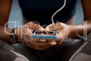 Shuffling through her beast mode playlist. Closeup shot of an unrecognisable woman using a cellphone while exercising in a gym.