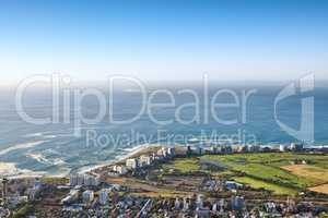 Landscape view of a beautiful coastal city near the beach on a summer day. Aerial view of a popular tourist urban town with greenery and nature during summer. Top view ocean and residential buildings