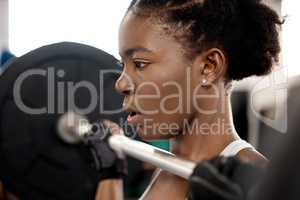 Feel weak Think strong. a sporty young woman exercising with a barbell in a gym.