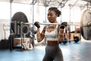 Strong women only intimidate weak men. a sporty young woman exercising with a barbell in a gym.