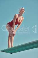 Keep your eyes on the prize. Full length shot of an attractive young female athlete standing on a diving board outside.