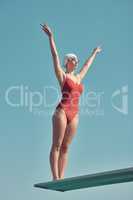Focus and perfection in form. Full length shot of an attractive young female athlete standing on a diving board outside.