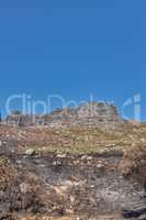 The aftermath of a natural mountain landscape destroyed by wildfire destruction on table mountain in Cape Town, South Africa. Burnt bushes, shrubs, plants, and vegetation after a fire disaster