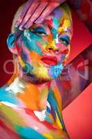 Think outside of the lines and live colourfully. Studio shot of a young woman posing with multi-coloured paint on her face.
