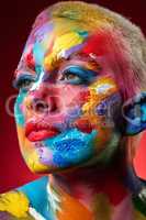 Yellow breeds happiness. Blue has a calming effect. Red symbolizes love. Studio shot of a young woman posing with multi-coloured paint on her face.
