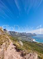 Famous mountain hiking trail with copy space, rough rocks or stones leading to scenic view of Twelve Apostles in Cape Town. Landscape of ocean, sea and coastal city with blue sky from nature reserve