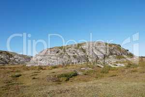 Scenic landscape of Bodo in Nordland with natural surrounding and blue sky copyspace background. Rock formation on mountain and hill with dry barren plants. Hiking trails in the countryside of Norway