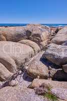 Boulders at a beach shore with the majestic ocean horizon..Copyspace at sea with blue sky background and rocky coast in Camps Bay Cape Town, South Africa with scenic landscape for a summer holiday