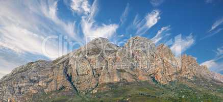 Landscape view of a mountainside with copy space and blue sky background from a lush, green botanical garden or national park. Low angle of rough, rocky, or dangerous terrain in a remote location