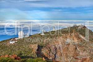 Observatory to look at the cosmos on the mountain near the beach with copy space. Peaceful and scenic landscape at the sea with a peak or rock hill and blue sky background outdoors in nature