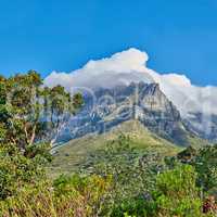 Peaceful nature in harmony with soothing views of plants and landscape. Thick clouds covering Table Mountain in Cape Town on a sunny day. Cloud shapes and shadows passing over rocky terrain