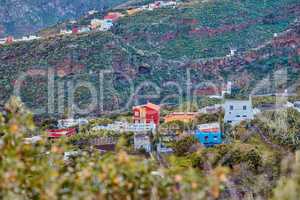 Architectural colorful buildings of a small hidden town in the mountains. The landscape of a colorful village on the outskirts of nature near a hill. Scenic view of bright buildings near foliage
