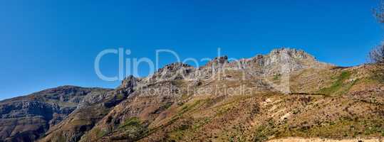 Twelve Apostles at Table Mountain in Cape Town against a blue sky background from below. Breathtaking view of plants and shrubs growing around a majestic rocky valley and scenic landmark in nature