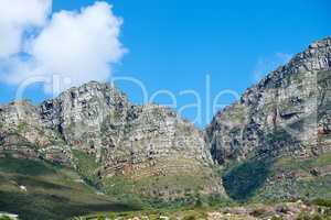 Scenic landscape of mountains in Western Cape, South Africa against a cloudy blue sky background with copyspace. Scenic of plants and shrubs growing on a rocky hill and cliff in a natural environment