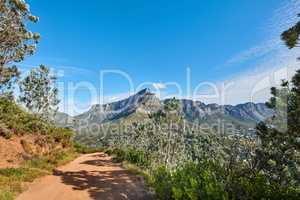 Scenic hiking trail in nature with Table Mountain against a blue sky copy space background. Rugged and sandy path to explore during a walk in fresh air. Remote and quiet landscape in the wilderness