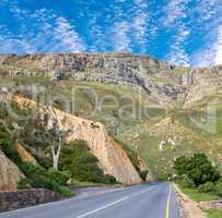 Landscape view of an empty and quiet road in the mountain for traveling and exploring on getaway vacations during summer. Scenic and secluded street in countryside against a blue sky with copyspace