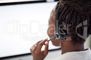 Our agents will assist you without delay. Rearview shot of a young call centre agent working on a computer in an office.