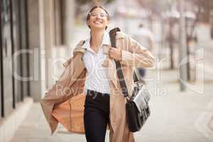 Even the heaviest cloud has to lift. a young businesswoman happily walking outside while out in the city.