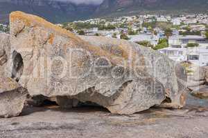 Boulders on the rocky coast of Western Cape, South Africa, Landscape view of a beautiful mountain, houses, and hotels in Cape Town. Natural environment in a popular tourist location for a holiday