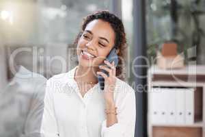 I knew Id get this call. a young businesswoman talking on her cellphone while standing in a office.