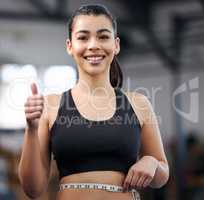 Choose to lose. Portrait of a fit young woman measuring her waistline in a gym.