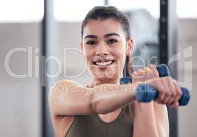 Feeling fit and looking fabulous. Portrait of a young woman working out with dumbbell weights in a gym.