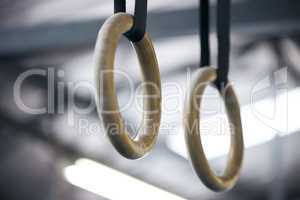 Grab hold and give it all youve got. a gymnastics ring hanging in an empty gym.