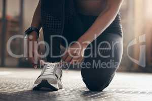 Im always ready. Closeup shot of an unrecognisable woman tying her laces while exercising in a gym.