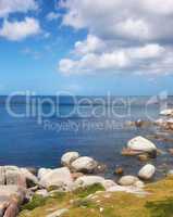 Scenic ocean view of beach with rocks or boulders and sea water washing onto shore during peaceful summer vacation in tropical resort and island overseas. Rough texture and detail of rocky coastline