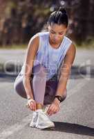 Proper running shoes are important. Full length shot of an attractive young female athlete tying her laces while out for a run.