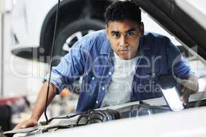 Just a simple manly man. Portrait of a handsome young male mechanic working on the engine of a car during a service.