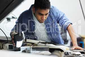 Well have to run a more thorough check. a handsome young male mechanic working on the engine of a car during a service.