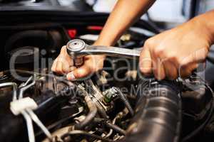 Whats that rattling noise. an unrecognizable male mechanic working on the engine of a car during a service.