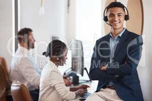 My team are trained to handle any inquiry. Portrait of a young call centre agent working in an office with his colleagues in the background.