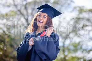 Heres to my next adventure. Portrait of a young woman holding her diploma on graduation day.