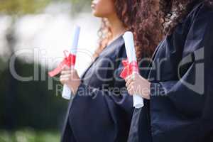 Keep venturing on through your journey. Closeup shot of two unrecognisable students holding their diplomas on graduation day.