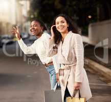 hang on sale, were on our way. two young women calling a cab after shopping against an urban background.