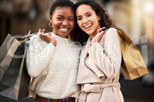 Give us a good bargain any day. Portrait of two young women shopping against an urban background.