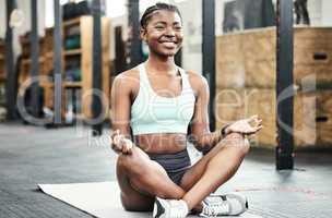 Time to bring my focus back to the present. Full length shot of an attractive young woman sitting in the gym and meditating after her workout.